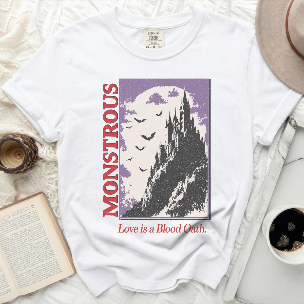 White t-shirt with "MONSTROUS" and a castle graphic with bats.