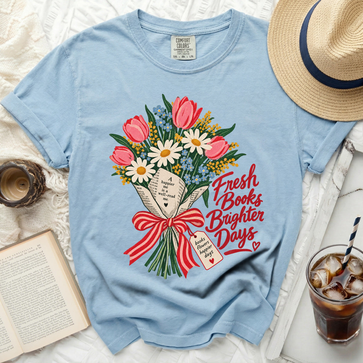 Light blue t-shirt with floral bouquet on book pages and text "Fresh Books Brighter Days".