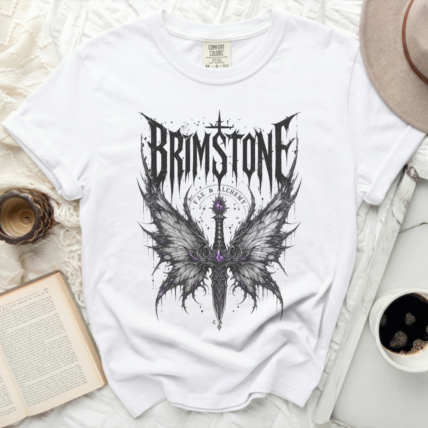 White t-shirt with black gothic dragon wing and sword graphic and "BRIMSTONE FAE & ALCHEMY" text.