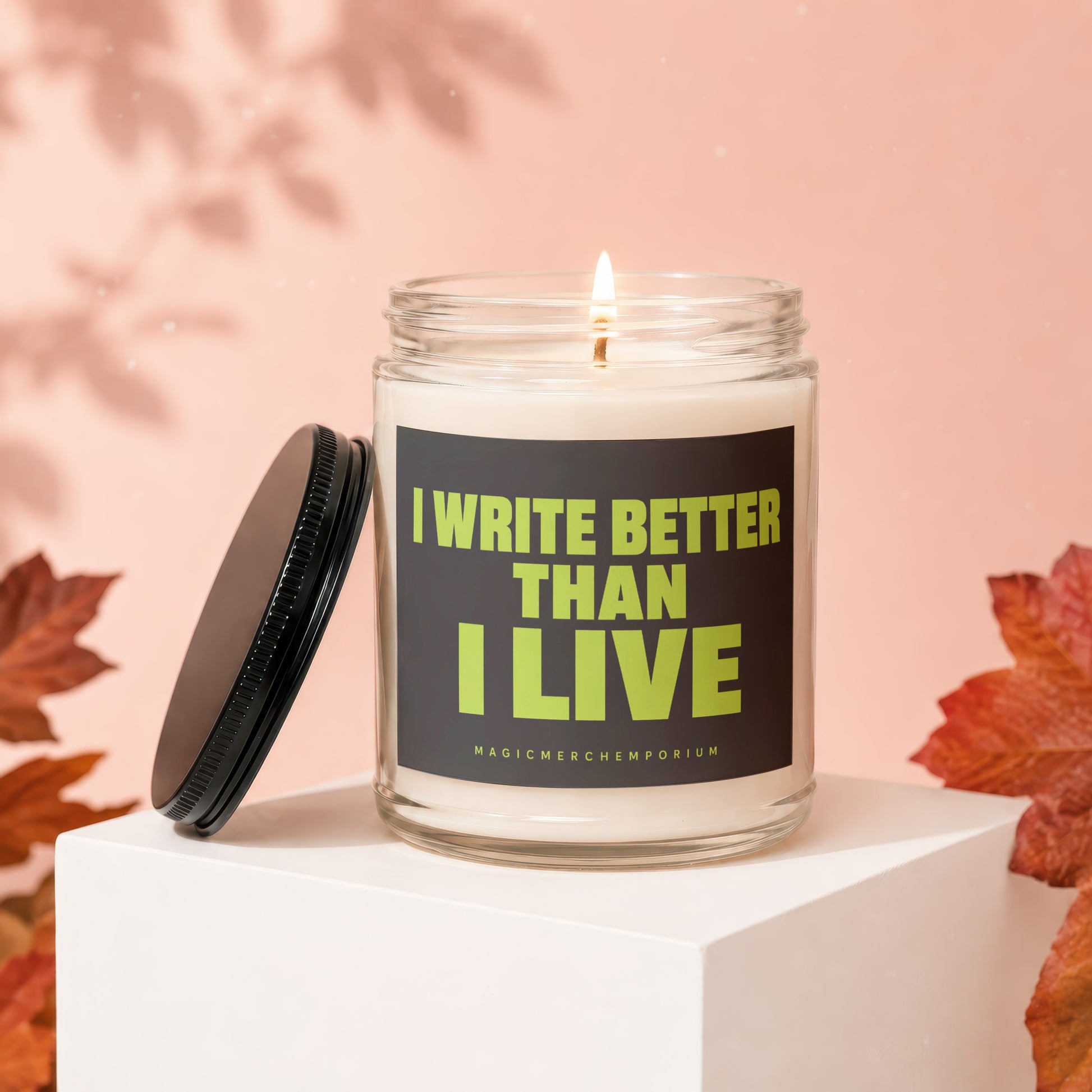Candle with lit wick and lid off, text reads "I WRITE BETTER THAN I LIVE".