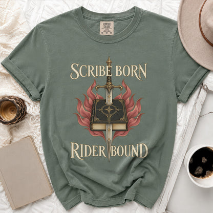 A muted green t-shirt with a graphic of a book pierced by a sword, surrounded by red flames, and the text Scribe Born Rider Bound.