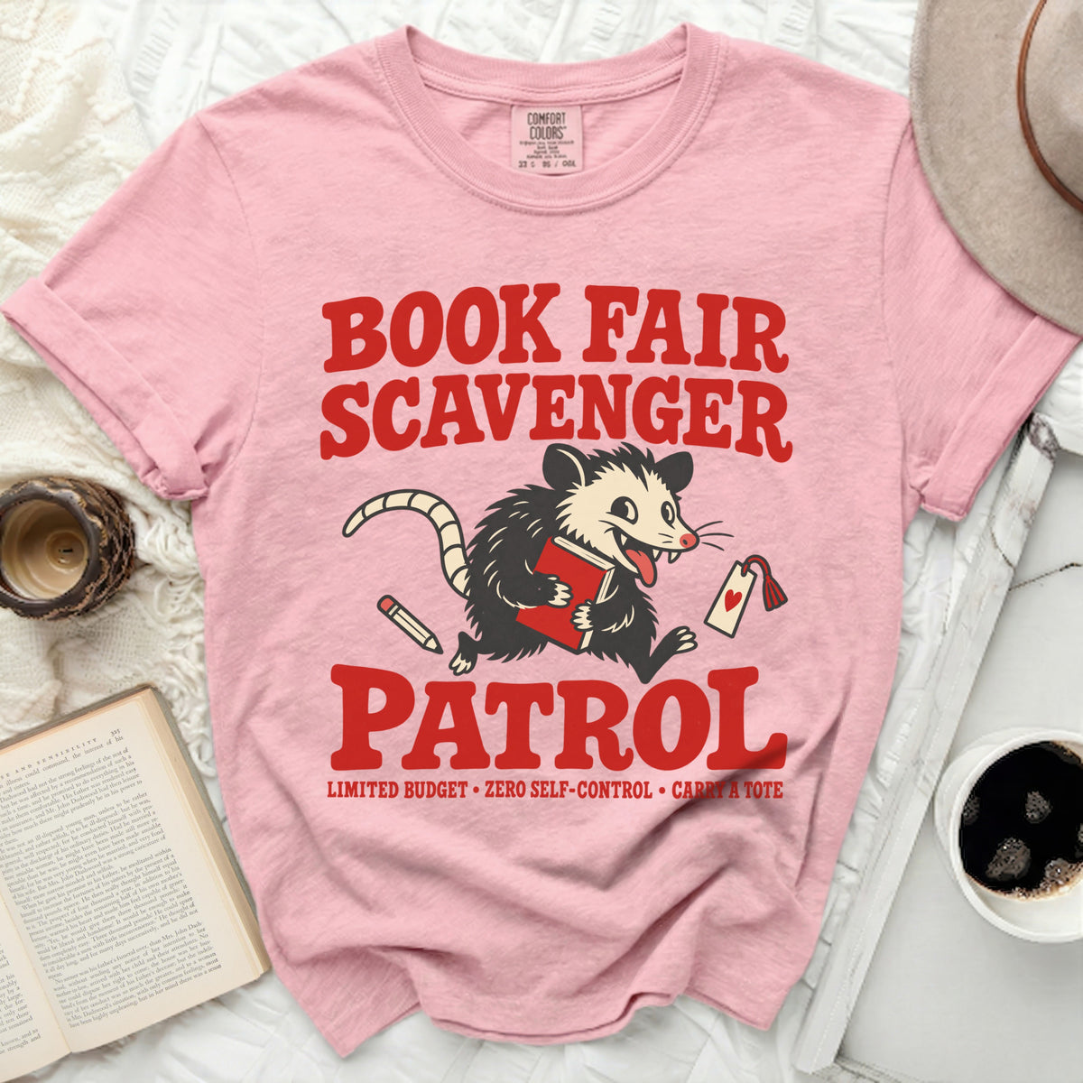 Pink t-shirt with red text: "BOOK FAIR SCAVENGER PATROL" and a possum holding a book.