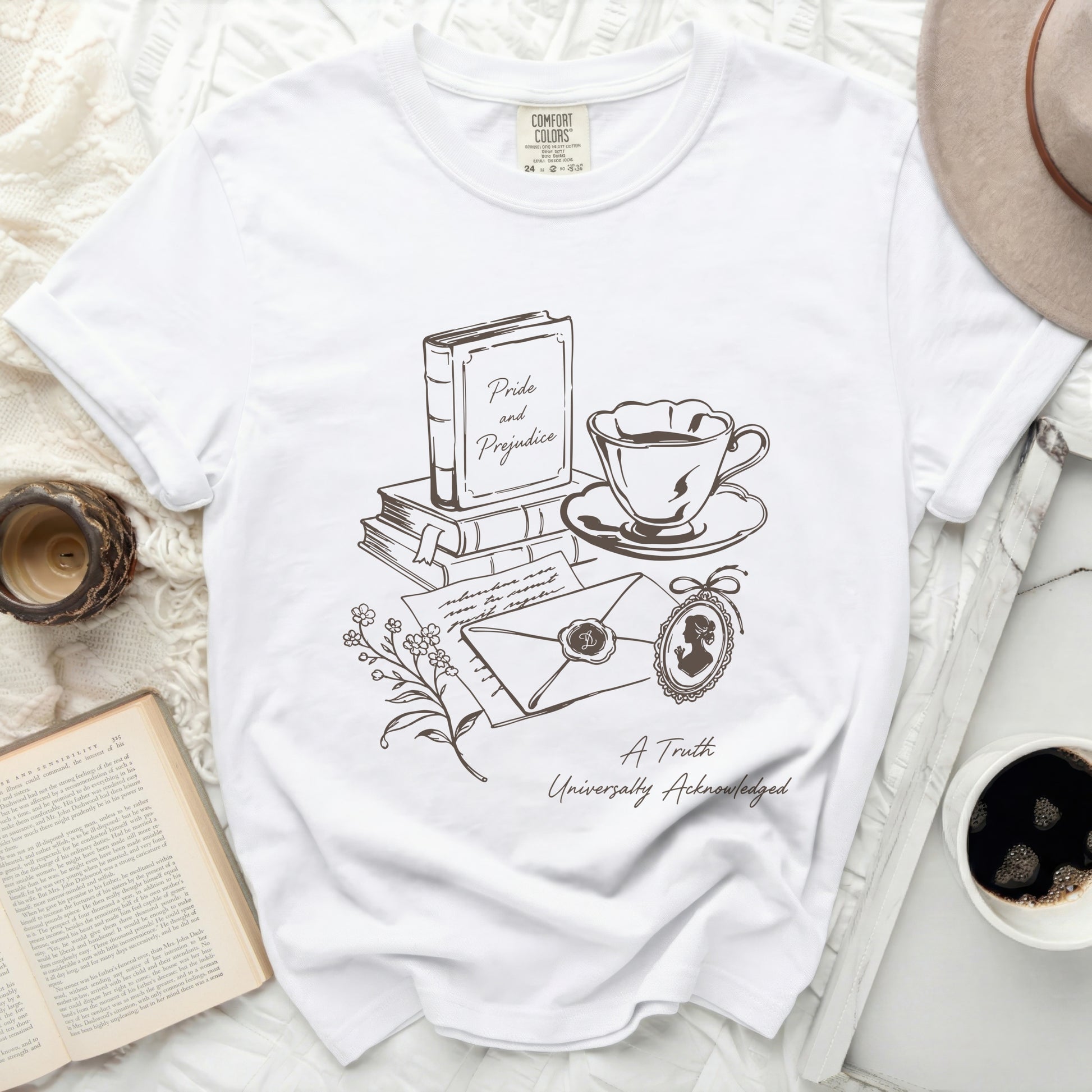 White t-shirt with a line drawing of books, "Pride and Prejudice," and coffee.