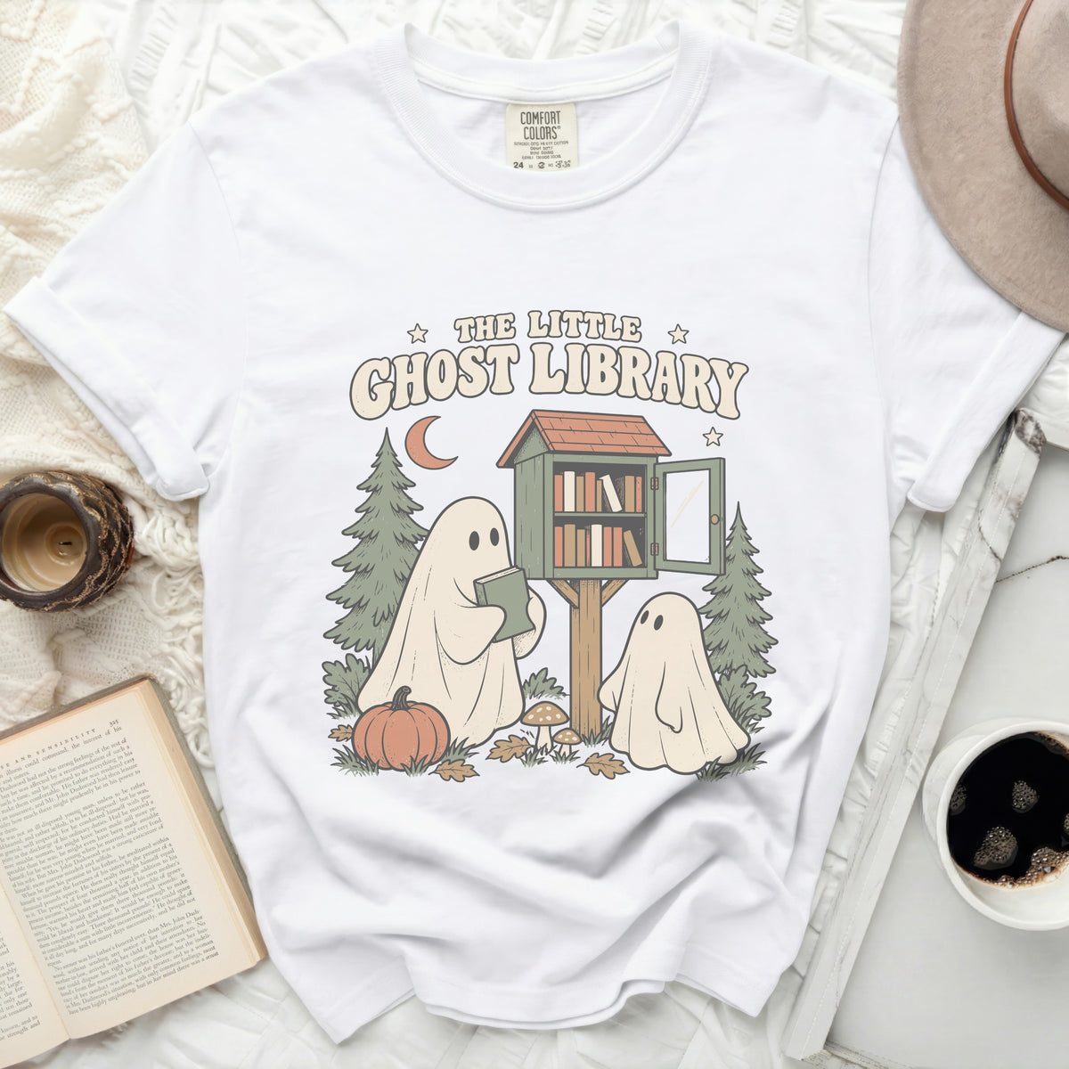 White t-shirt with "The Little Ghost Library" graphic featuring ghosts and a book exchange.