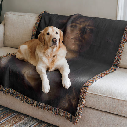 A golden retriever dog is lying on a black and brown throw blanket on a beige couch.