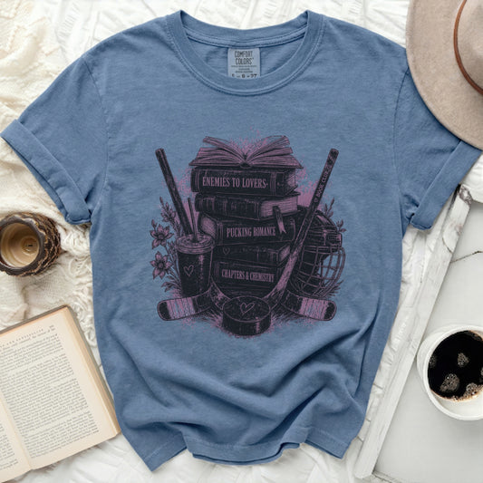 T-shirt with books, hockey sticks, and romantic novel themes.