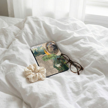 Book with fantasy map and illustration, glasses, and scrunchie on white sheets.