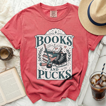 Coral t-shirt with "Books and Pucks" design featuring ice skates and hockey sticks.