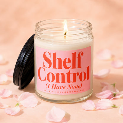 Candle with "Shelf Control (I Have None)" text on pink label, surrounded by petals.