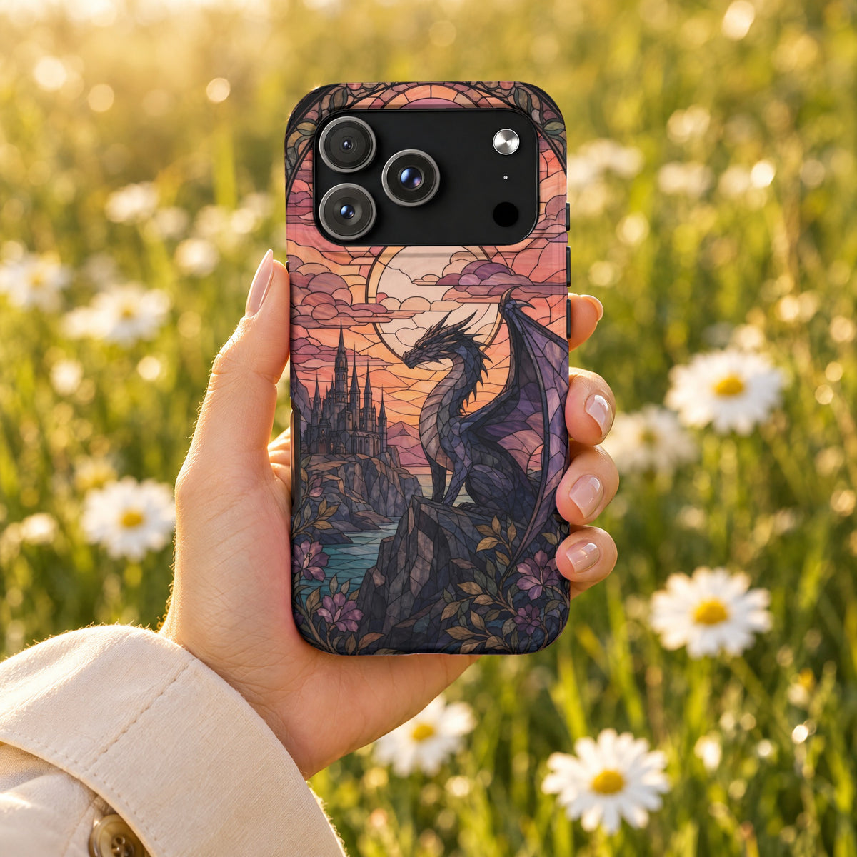 A hand holding a smartphone with a stained-glass style dragon and castle design, against a blurred floral background.