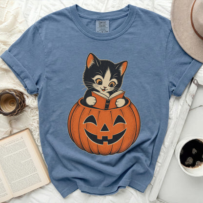 Blue t-shirt with a black and white kitten reading a book inside a pumpkin.