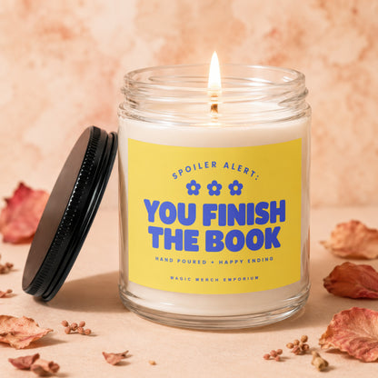 Scented candle with yellow label reading "Spoiler Alert: You Finish The Book".