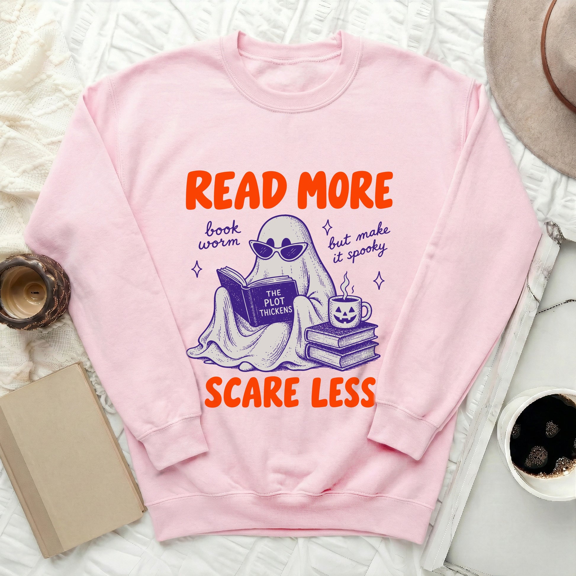 Pink sweatshirt with ghost reading a book and text: "Read More, Scare Less."