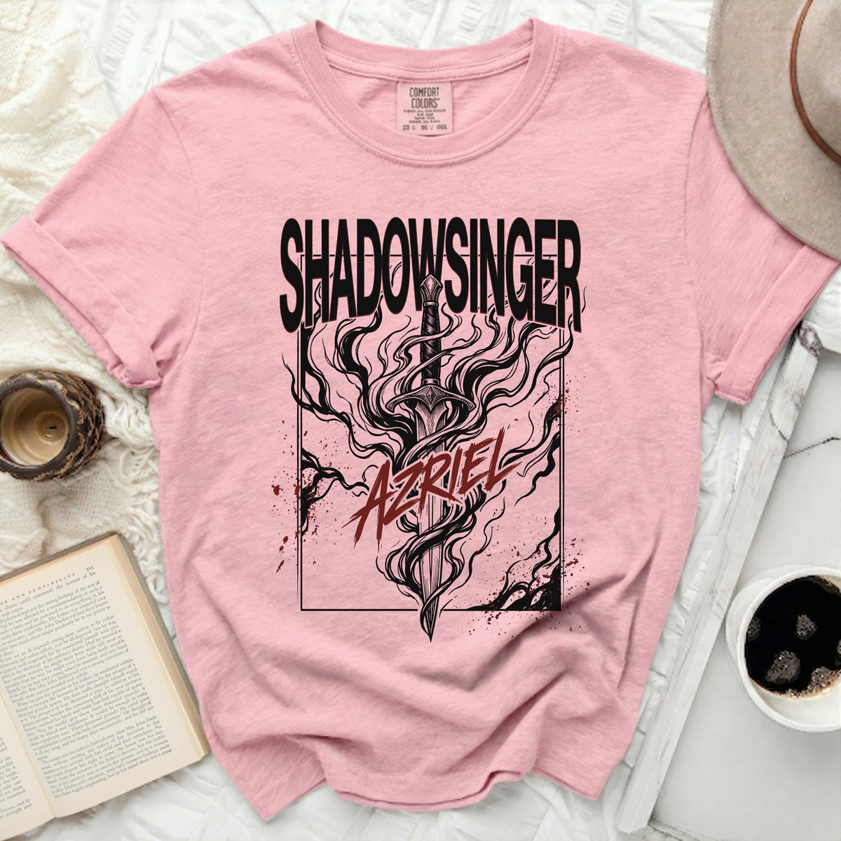Pink t-shirt with black "SHADOWSINGER" and "AZRIEL" graphic of a sword.