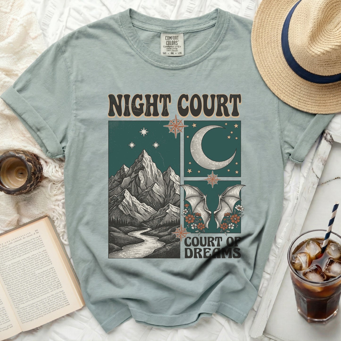 Light teal t-shirt with "Night Court" and "Court of Dreams" text and illustrated celestial mountain scene.