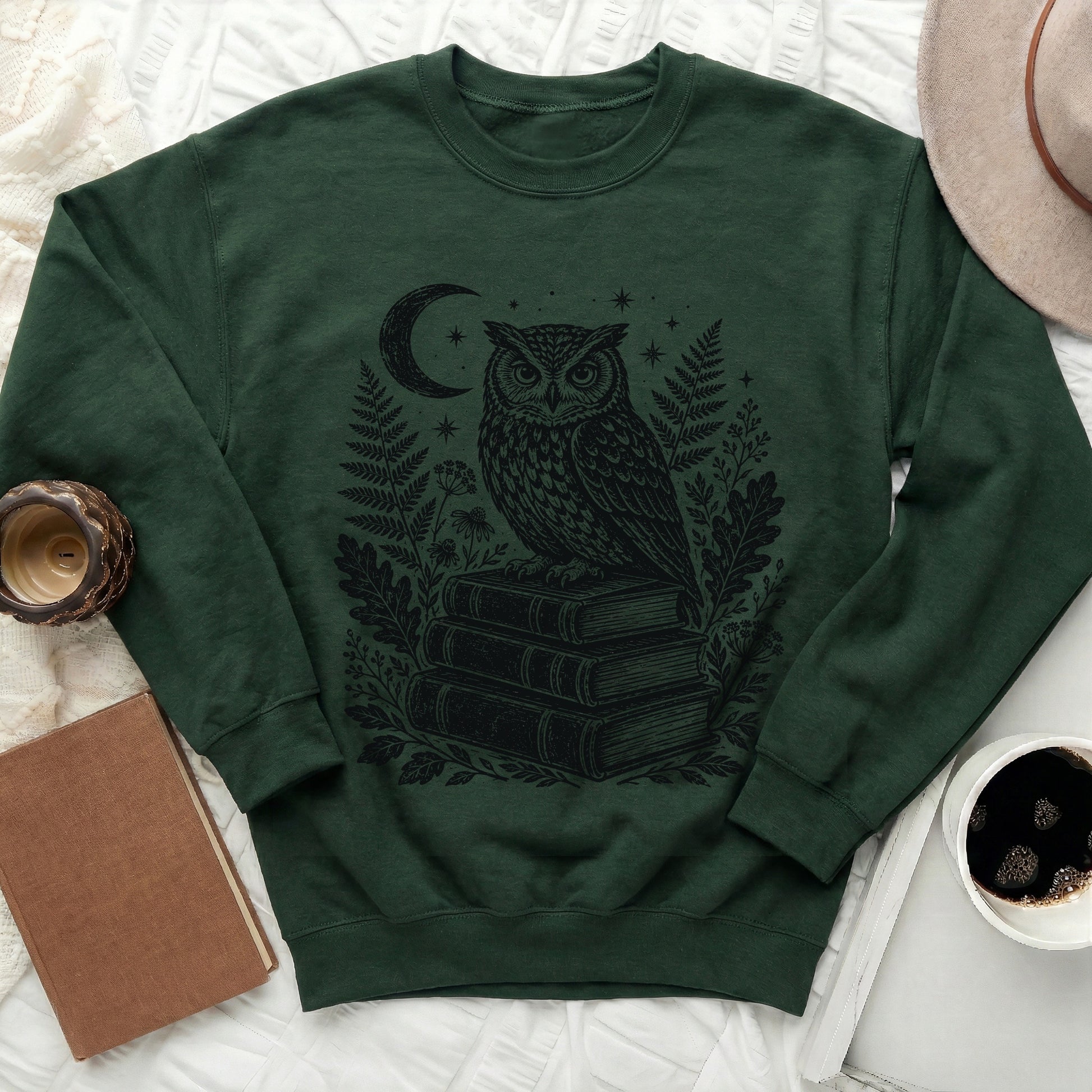 Green sweatshirt with black print of owl on books under moon and stars.