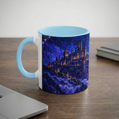 A white ceramic mug with a light blue handle and rim displays a stained-glass style castle at night.