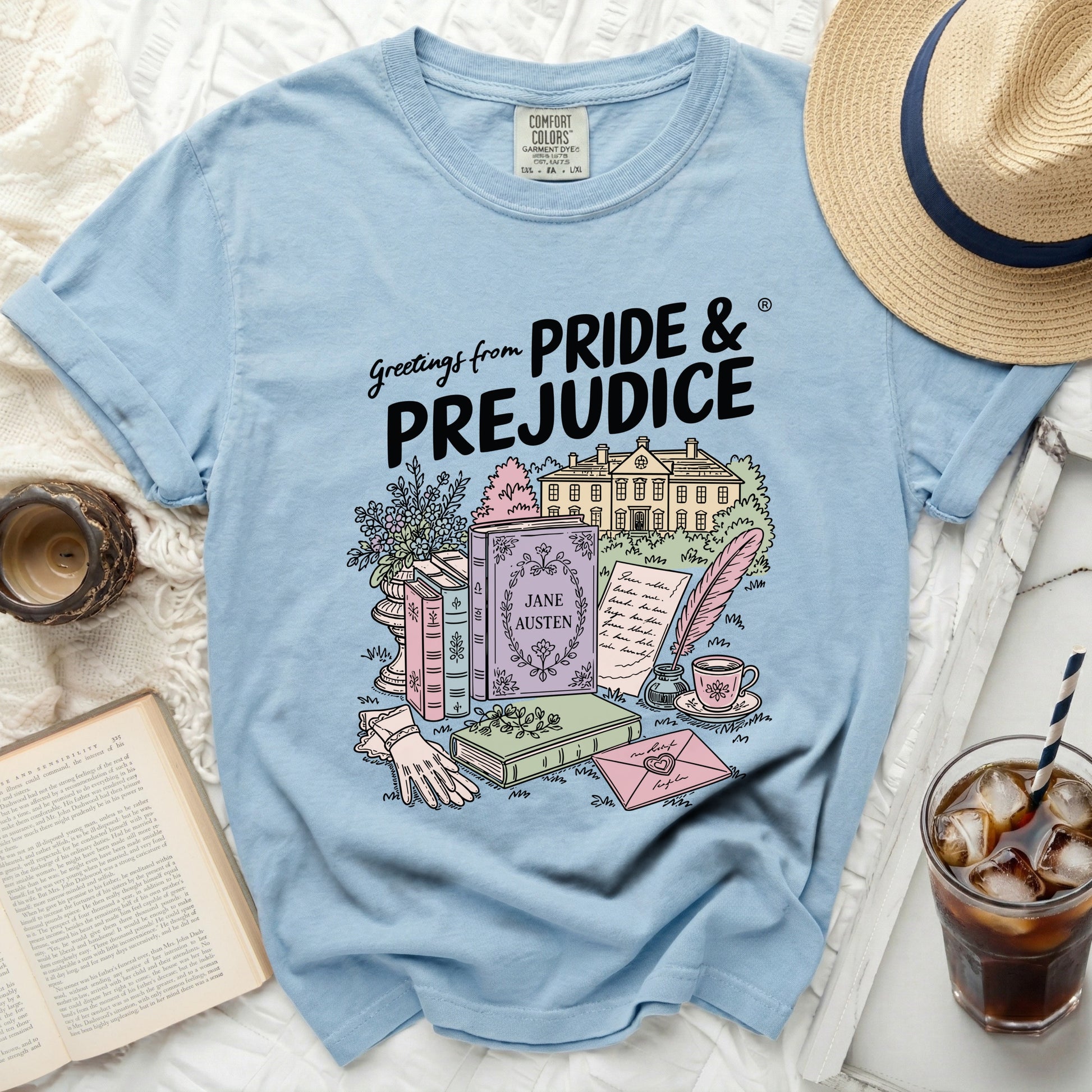 Light blue t-shirt with "Greetings from PRIDE & PREJUDICE" and an illustration.