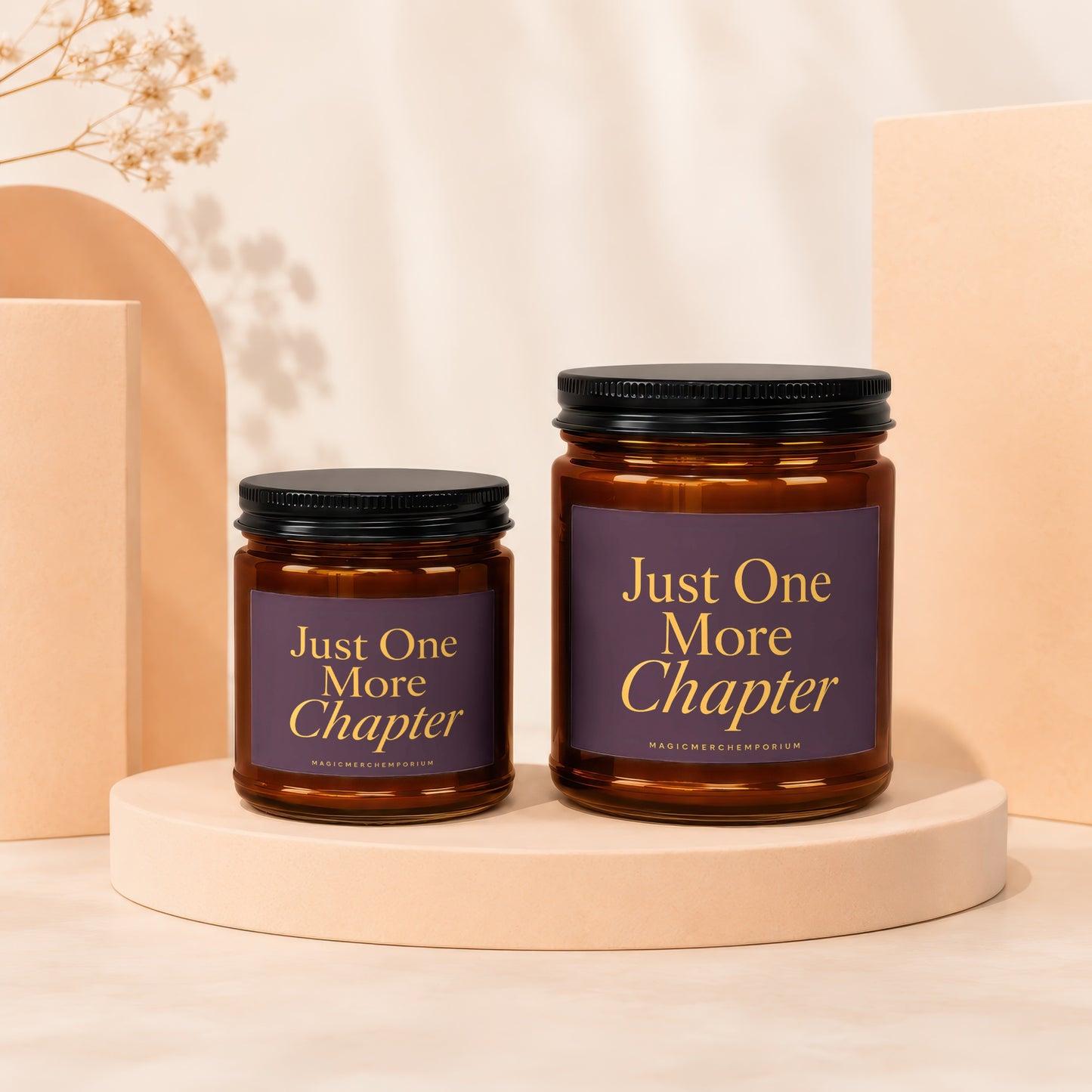 Two amber glass candles with black lids bear "Just One More Chapter" text.