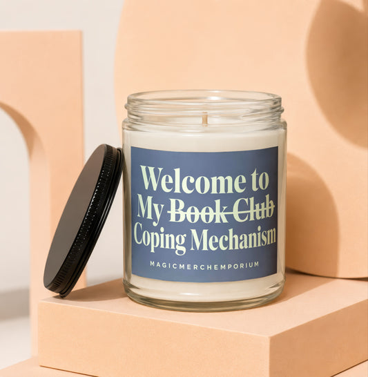 White candle in a glass jar with a dark blue label reading "Welcome to My Book Club Coping Mechanism".