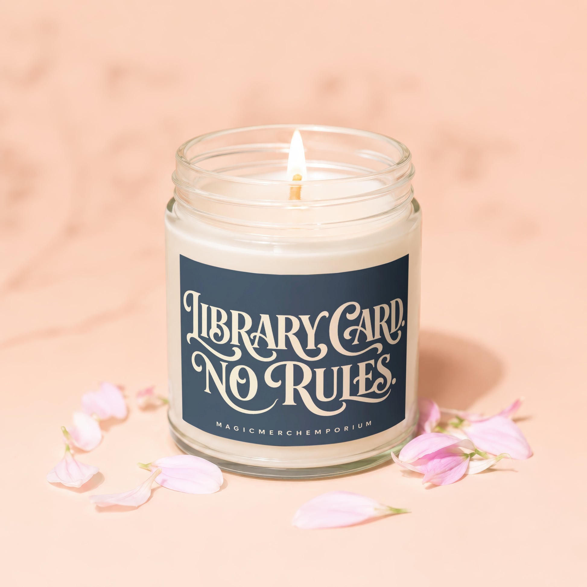Glass jar candle with lit wick, featuring "Library Card No Rules" text.