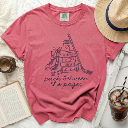 T-shirt with "puck between the pages" text and book, hockey, and ice skate graphics.