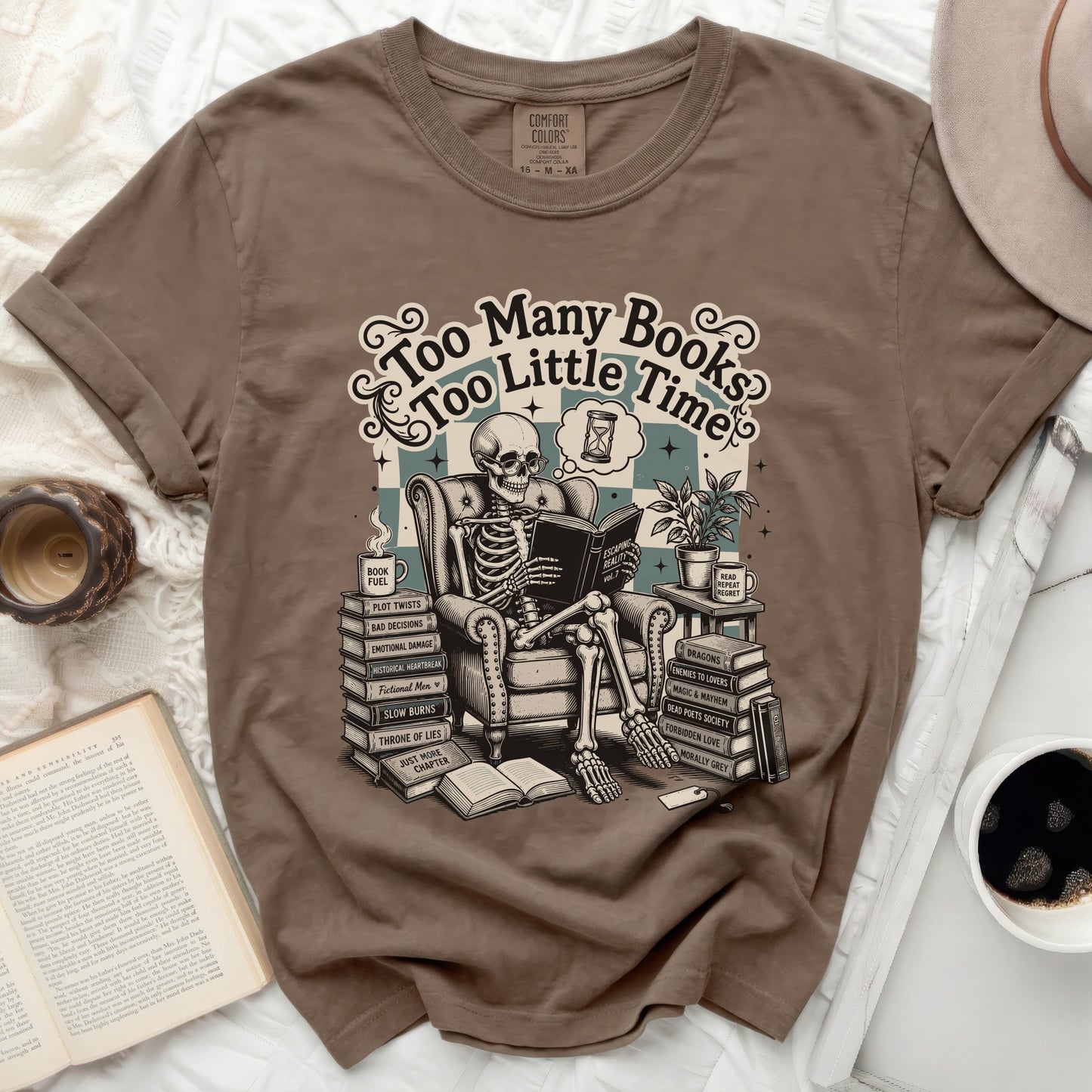 Brown t-shirt graphic of a skeleton reading "Too Many Books Too Little Time" with stacks of books.