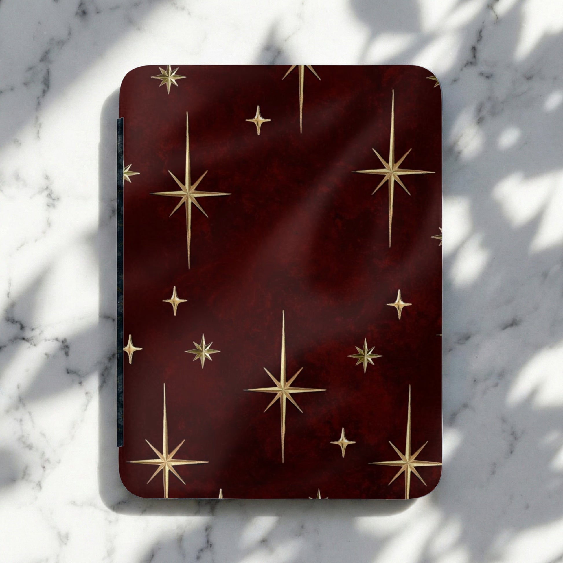 Dark red rectangular object with gold star pattern resting on a marble surface.