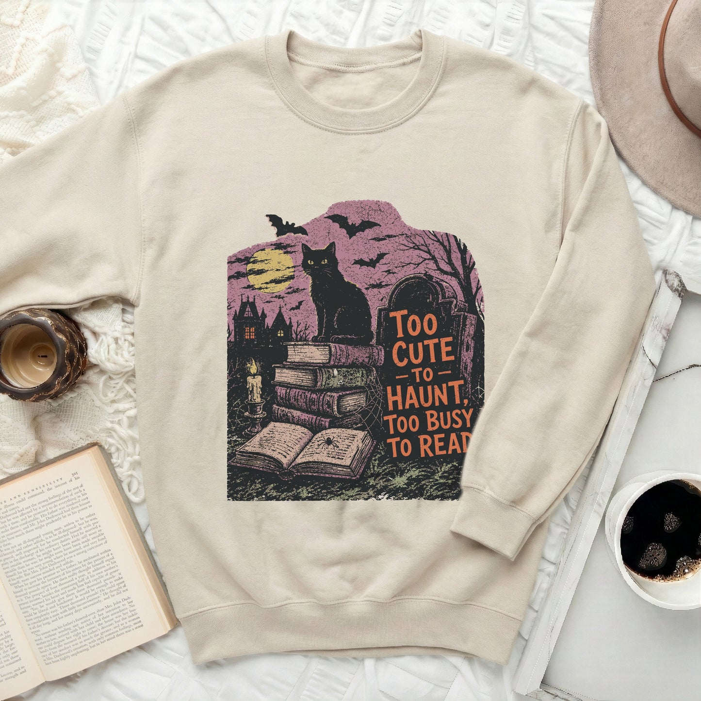 Black cat on books with "Too cute to haunt, too busy to read" text.
