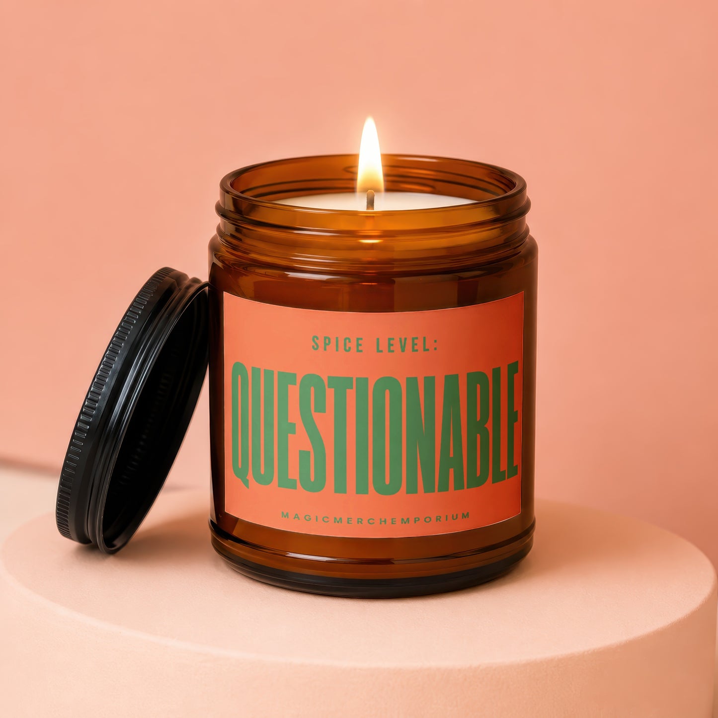 Amber jar candle with lit wick and black lid, reads "SPICE LEVEL: QUESTIONABLE MAGICMERCH".