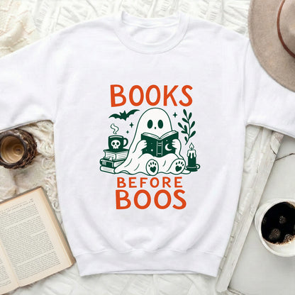 White sweatshirt with "BOOKS BEFORE BOOS" and a ghost reading a book graphic.
