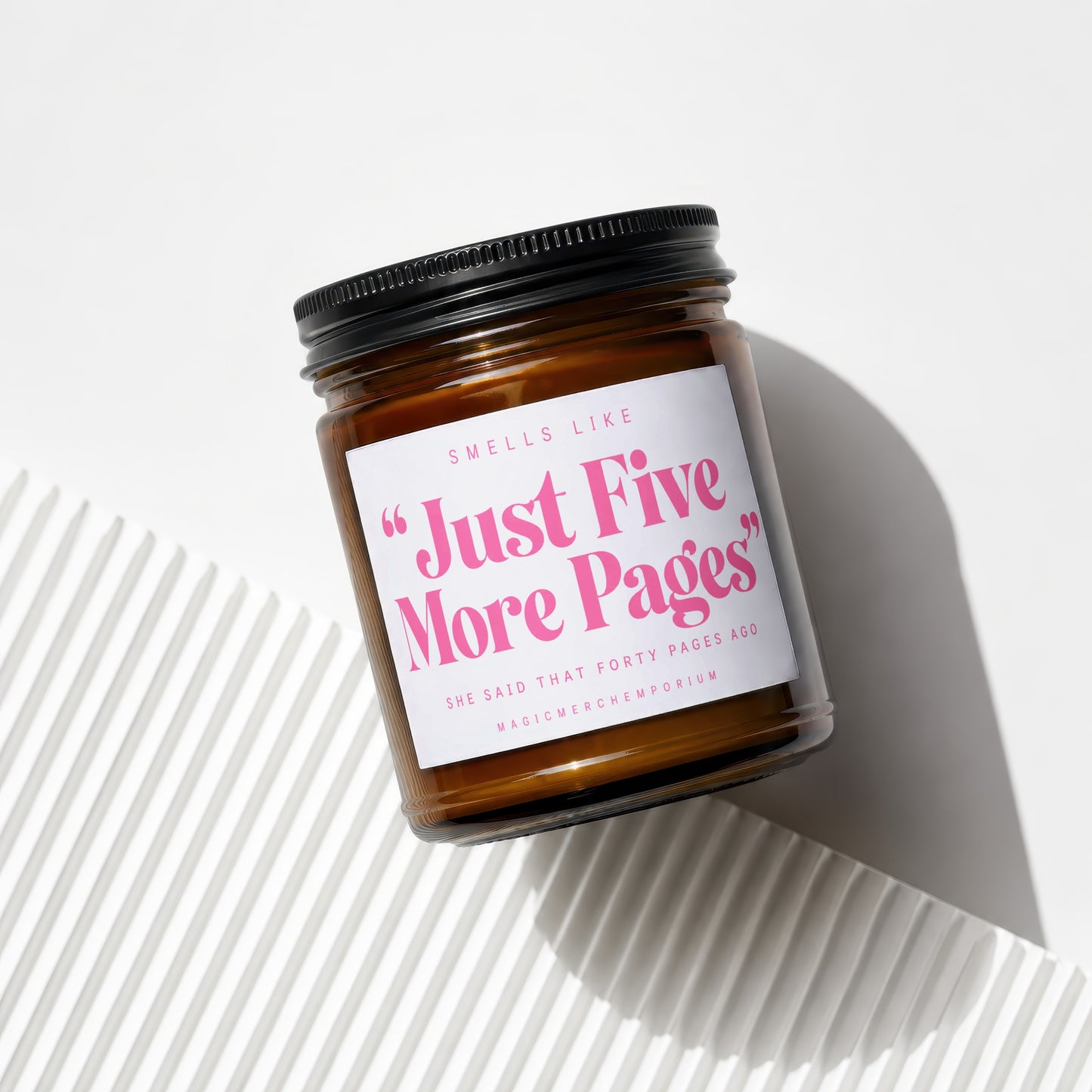 Amber jar candle with black lid labeled "Just Five More Pages".