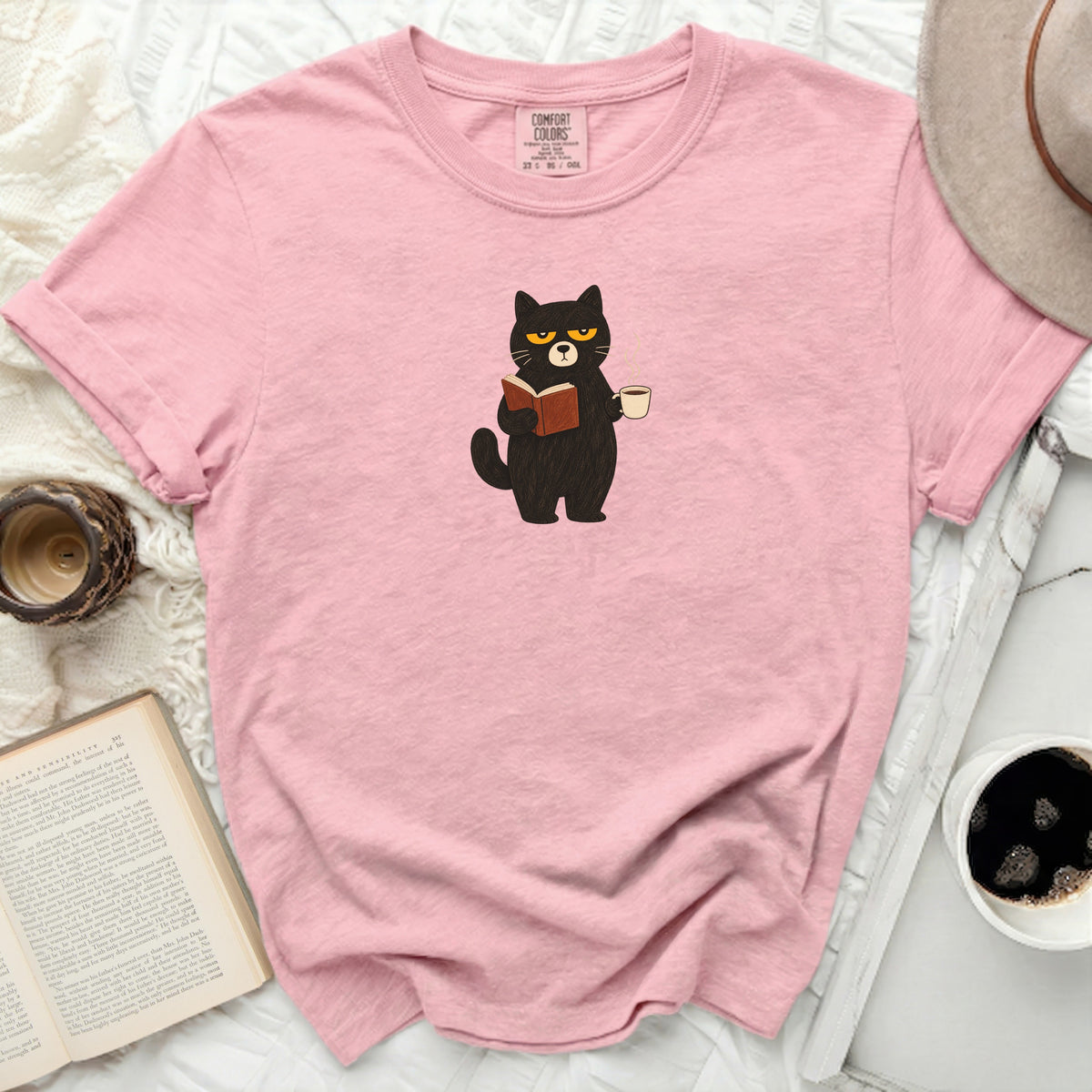 Pink t-shirt with black cat reading a book and holding coffee.
