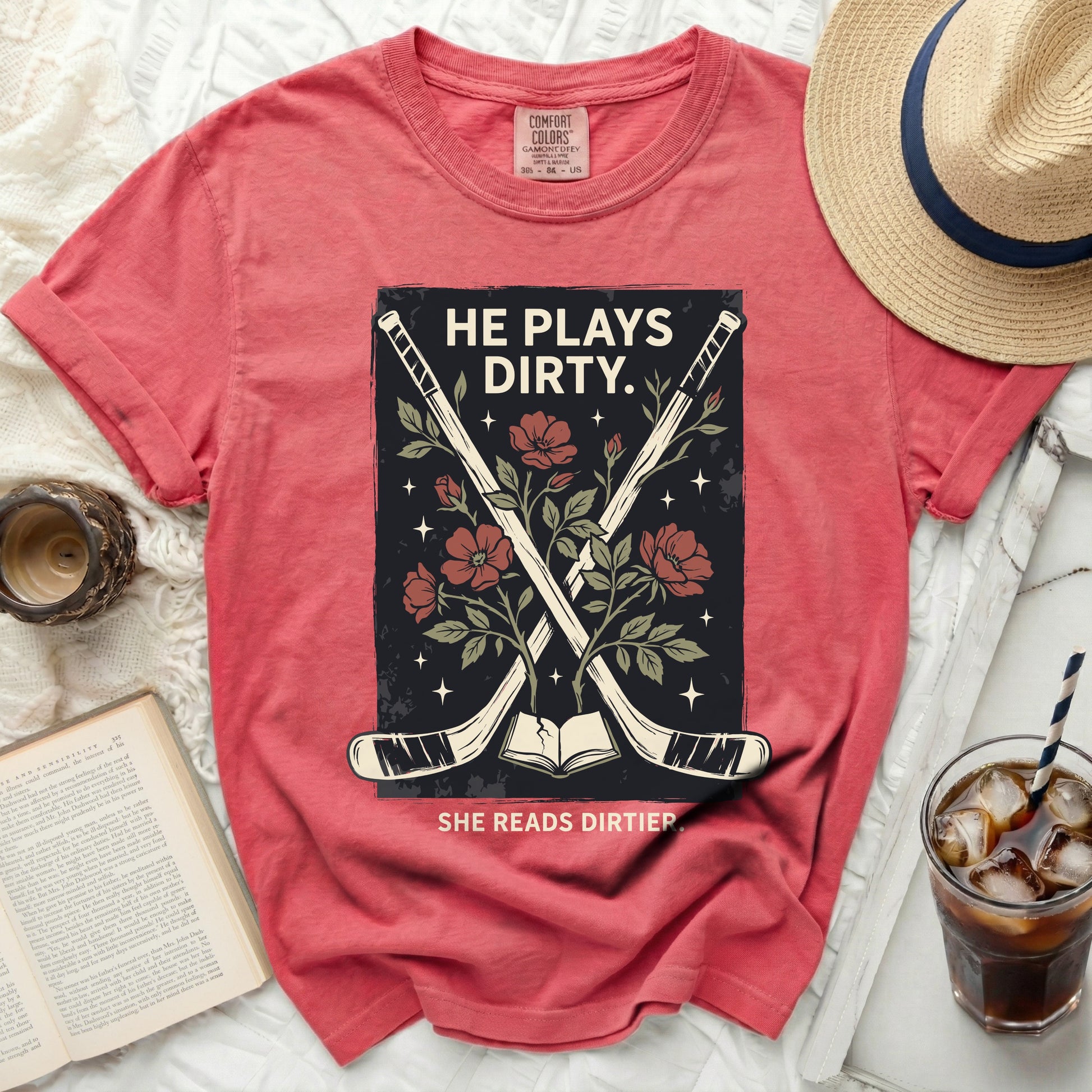 T-shirt with crossed hockey sticks, book, and flowers, reading "HE PLAYS DIRTY. SHE READS DIRTIER."