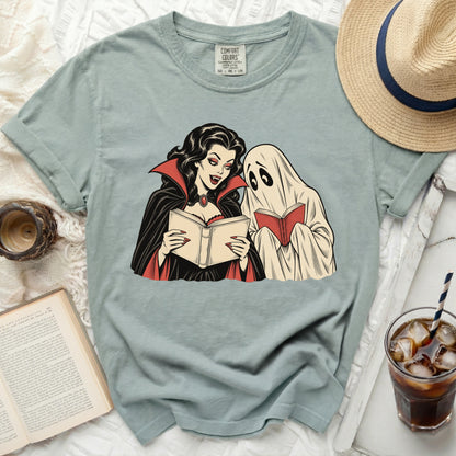 Vampire and ghost reading books on a light blue t-shirt with Comfort Colors tag.