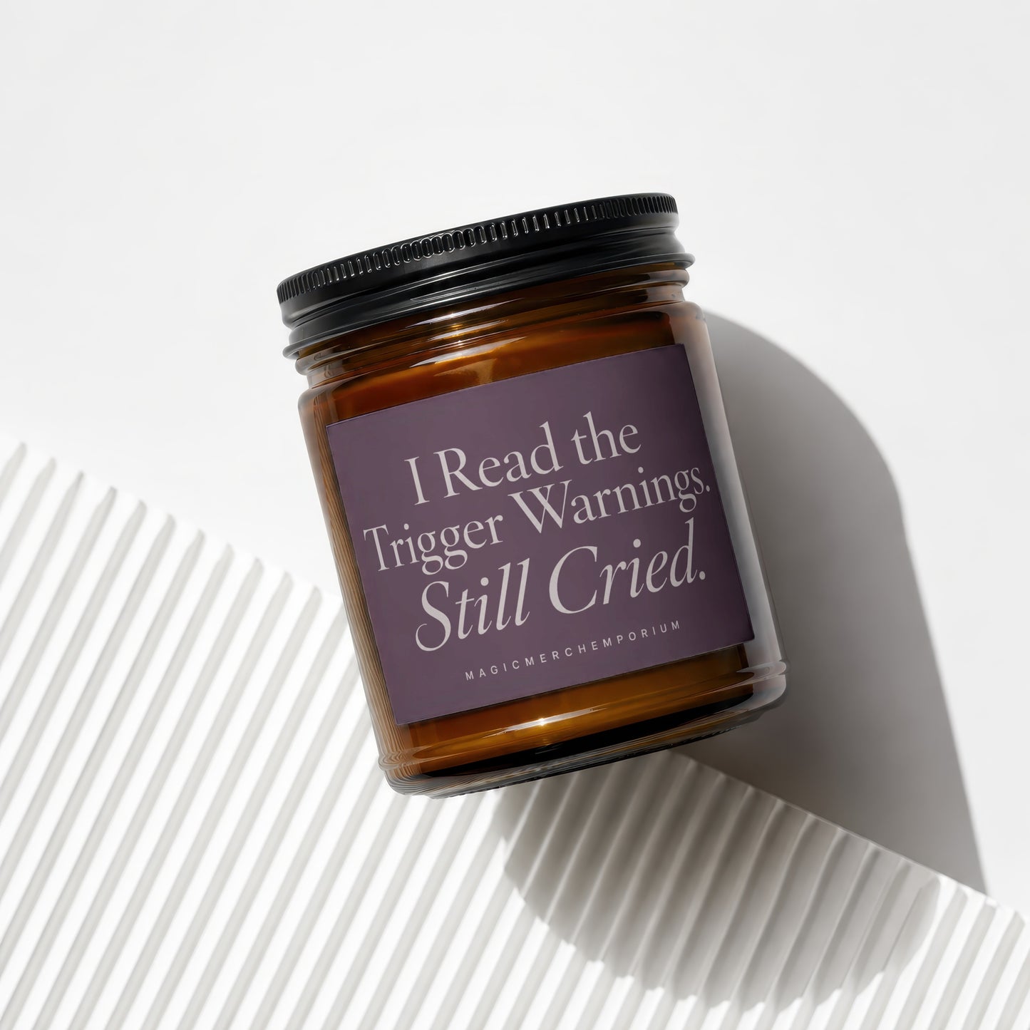 Amber glass candle with purple label reading "I Read the Trigger Warnings. Still Cried."