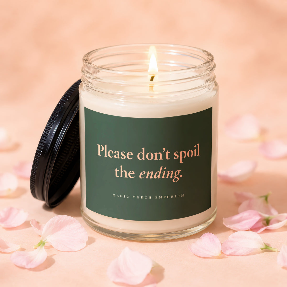 Lit candle in a glass jar with a black lid and green label reading Please don't spoil the ending.