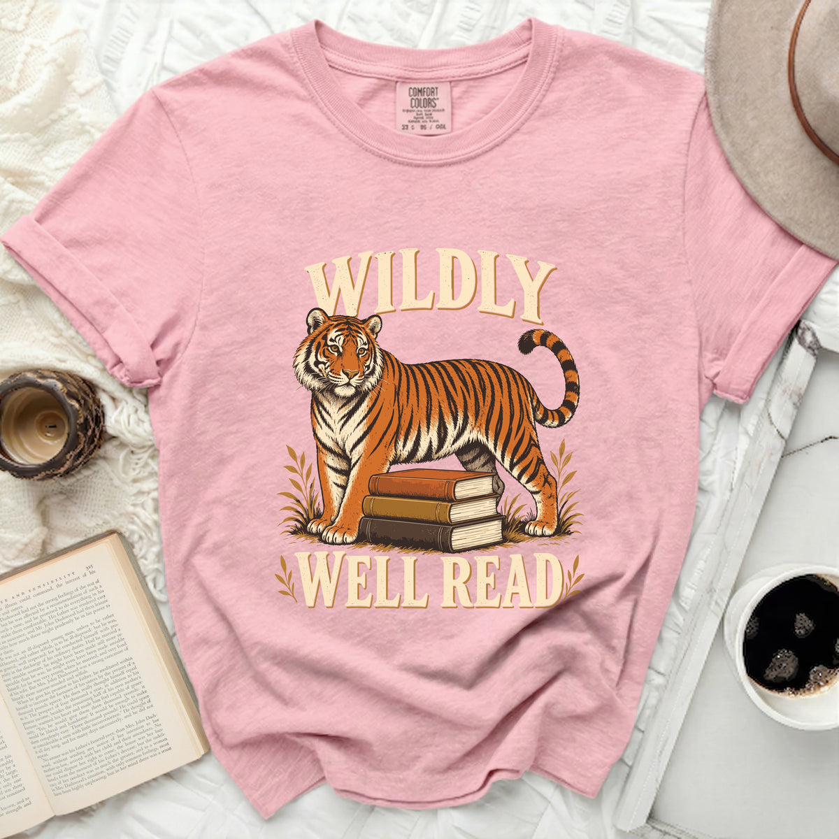 Pink t-shirt with graphic of tiger on books, text "WILDLY WELL READ".