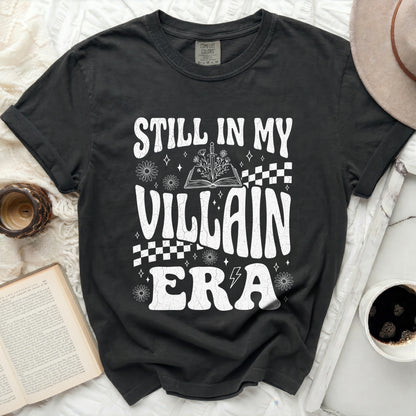 Black t-shirt with "STILL IN MY VILLAIN ERA" graphic and book imagery.
