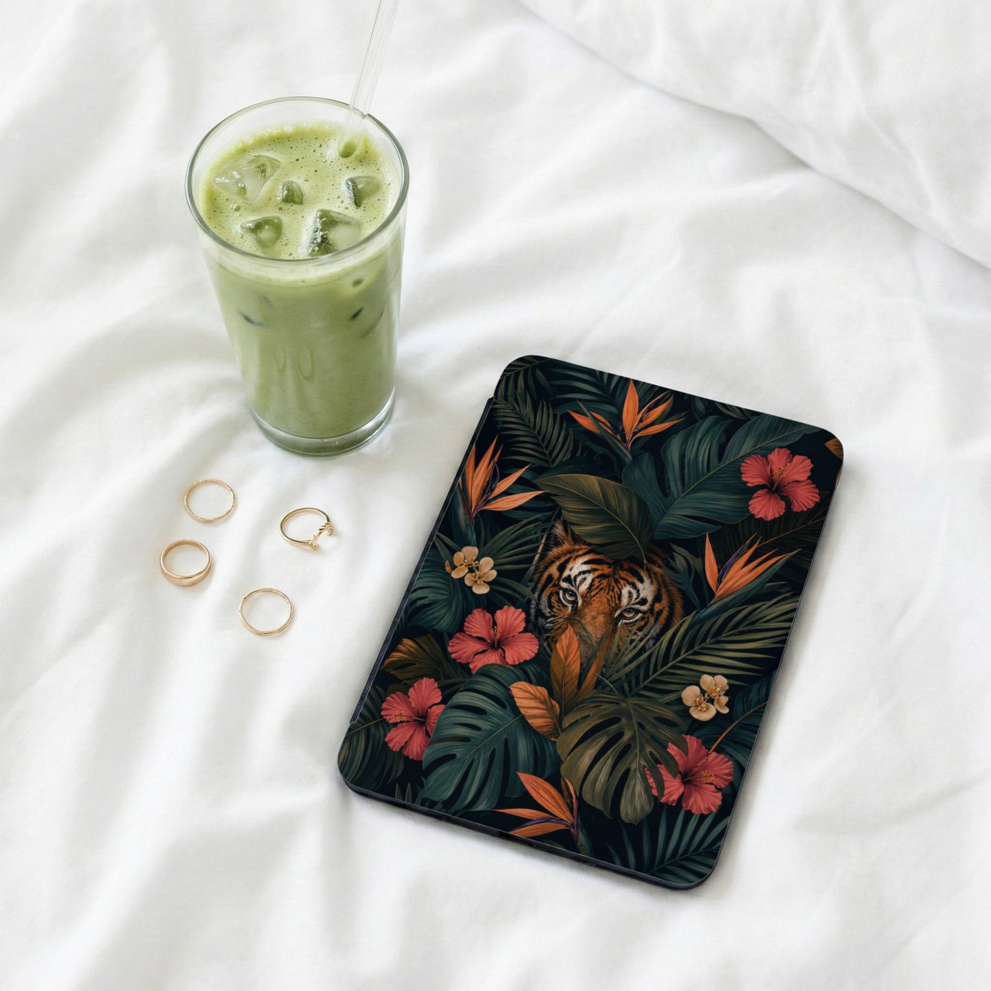 Ipad case with tiger and tropical flowers, next to a green drink and rings.