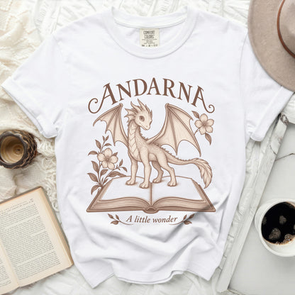 White t-shirt with a dragon on an open book. Text reads ANDARNA and A little wonder.