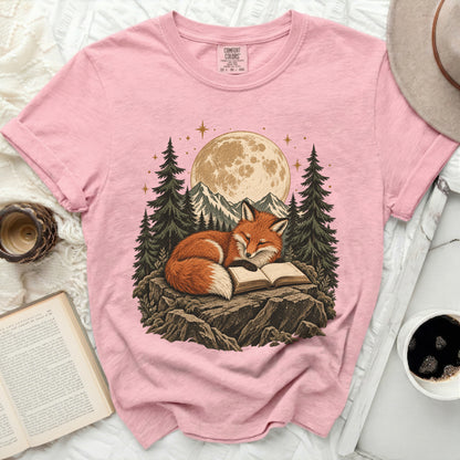 Pink t-shirt with a graphic of a fox reading a book under a moonlit sky.