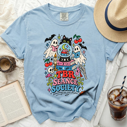 Light blue t-shirt with "TBR Seance Society" and spooky book-themed graphics.