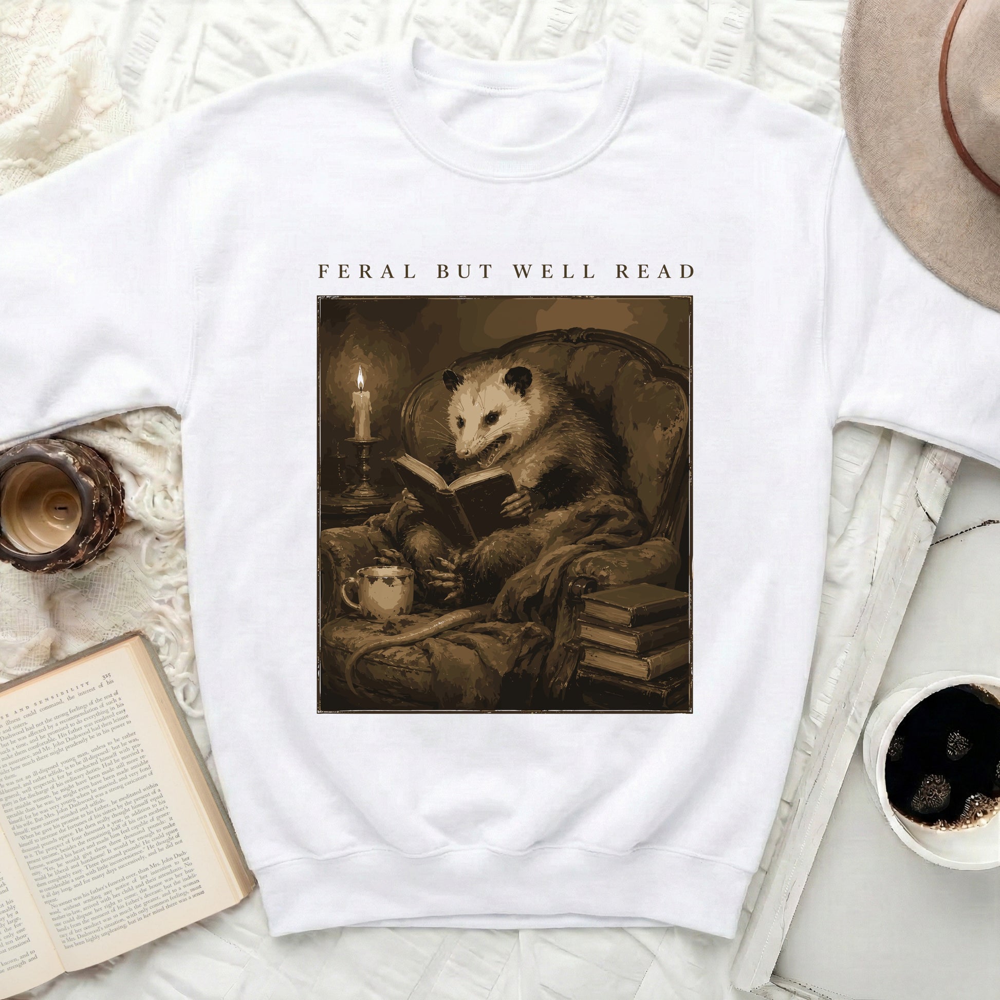 Opossum reading a book by candlelight with text "FERAL BUT WELL READ".