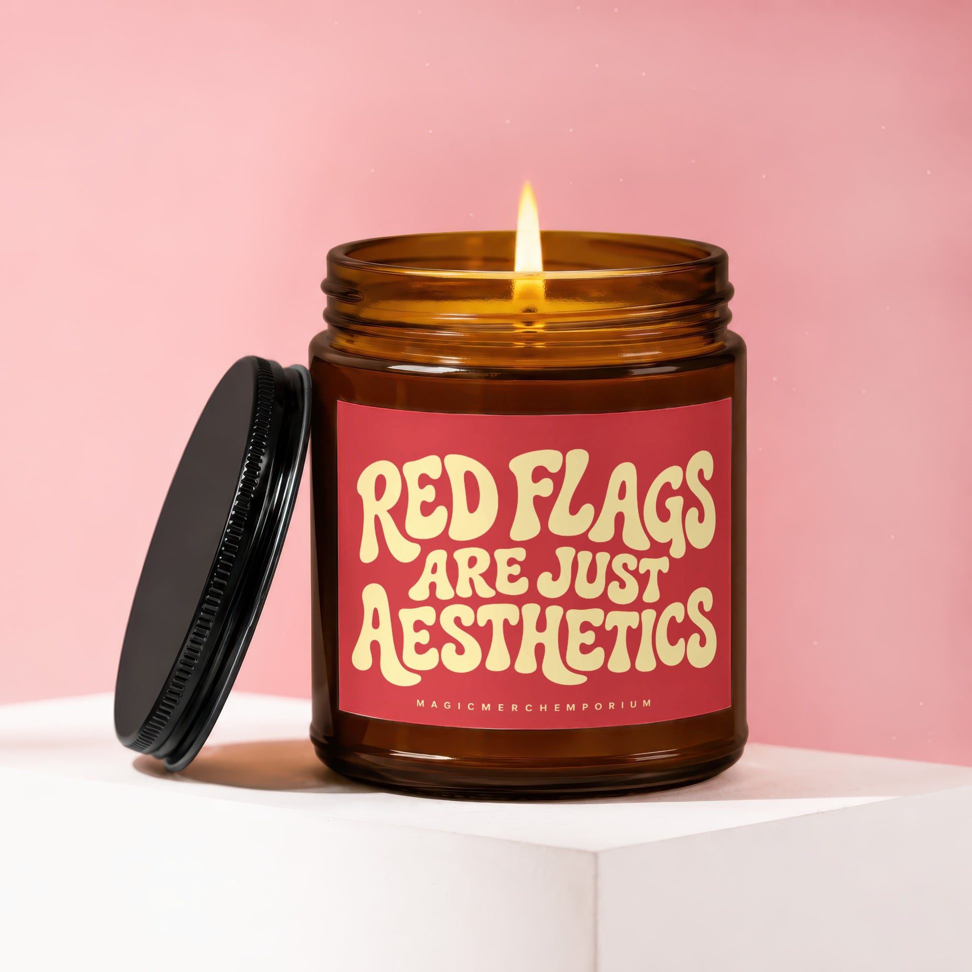 Lit amber glass candle with "RED FLAGS ARE JUST AESTHETICS" on label.