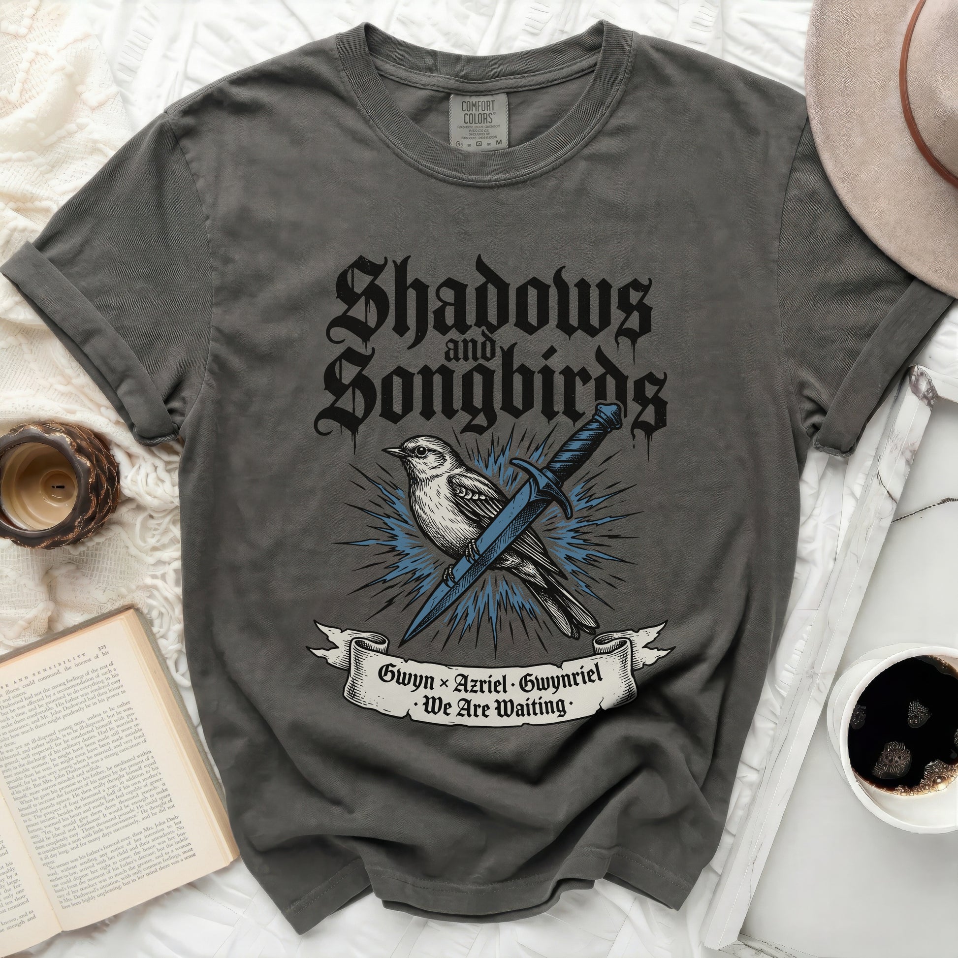 Dark grey t-shirt with "Shadows and Songbirds" and sword design.