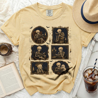 Yellow t-shirt with a graphic of skeletons reading books in ornate frames.