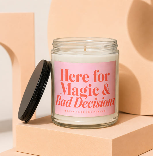 Glass candle with pink label reading "Here for Magic & Bad Decisions"