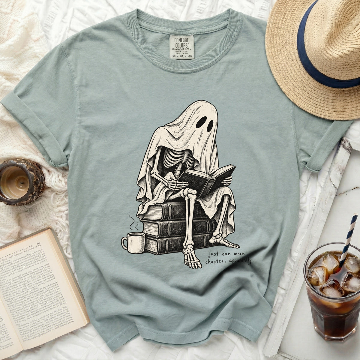Skeleton ghost wearing a sheet sits on books, reading, with text "just one more chapter, apparently."