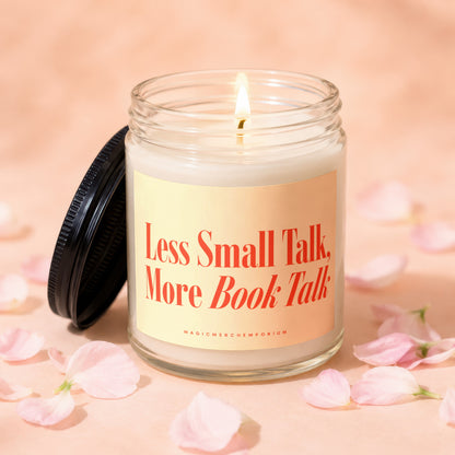 Candle with lit flame, lid off, on a light pink surface with scattered flower petals.